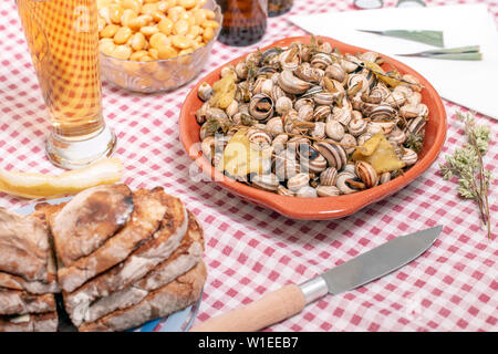 Portoghese tradizionale piatto di lumache cotte e pane tostato e birra. Foto Stock