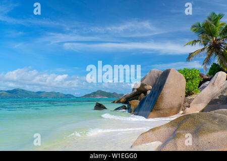 Onde turbinano intorno grandi massi di granito e le palme sulle Anse Source d'Argent, La Digue, Seychelles, Oceano indiano, Africa Foto Stock