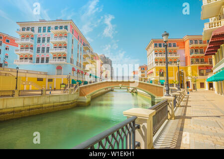 Bella Piccola Venezia con canali collegati da ponti in stile veneziano e case colorate in Qanat Quartier, Venezia presso la perla, Doha, Qatar Foto Stock