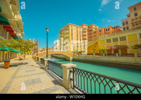 Bella Piccola Venezia con canali collegati da ponti in stile veneziano, Qanat Quartier, Venezia presso la perla nella luce del tramonto, Doha, Qatar Foto Stock