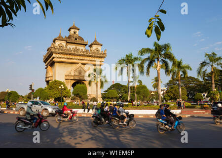 Ciclomotori passato di equitazione il Patuxai Monumento della Vittoria (Vientiane Arc de Triomphe), Vientiane, Laos, Indocina, Asia sud-orientale, Asia Foto Stock