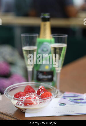 Una ciotola di fragole e crema con bicchieri di champagne e biglietti per il campo centrale il secondo giorno del Wimbledon Championships all'All England Lawn Tennis and Croquet Club, Wimbledon. Foto Stock