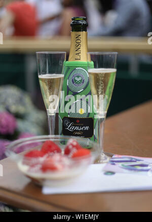 Una ciotola di fragole e panna con bicchieri di champagne e Centre Court biglietti il giorno due dei campionati di Wimbledon al All England Lawn Tennis e Croquet Club, Wimbledon. Foto Stock