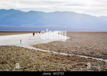 Persone che attraversano il bacino di Badwater, il bacino endorheic, Death Valley National Park, Inyo, California, USA Foto Stock