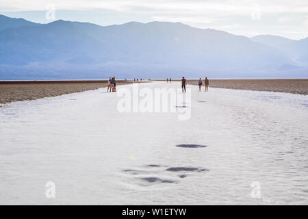 Persone che camminano attraverso il bacino di Badwater, bacino endorheic, Death Valley National Park, Inyo, California, USA Foto Stock