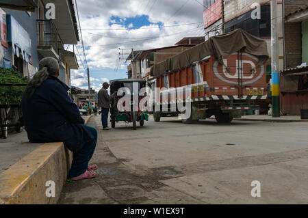 Chavín de Huantar, Ancash / Perù: 11 Giugno, 2016: vecchia donna guardando il ongoings sulla strada principale di Chavín de Huantar su un tipico occupato per i giorni feriali Foto Stock