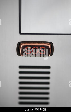 Il tasto SOS. Pulsante SOS close-up sul pannello del dispositivo, intercom. Guida tasto di chiamata sulla schermata del dispositivo in metallo grigio colore. Fotografia verticale Foto Stock