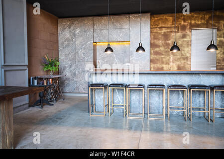 Industrial loft bar di stile. La camera ha un sacco di sedie a sdraio presso il bar ,quattro lampade a sbalzo, tavola di marmo Foto Stock