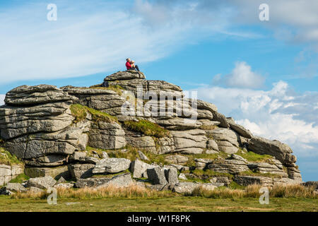 La donna e il suo cane nella parte superiore della cucitrice centrale Tor, Merrivale, Parco Nazionale di Dartmoor, Devon, Inghilterra, Regno Unito. Foto Stock