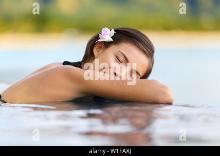 Donna di relax in hotel di lusso piscina sulle vacanze - Vacanze viaggi. Asian femmina giovane persona che dormiva nella piscina spa presso hotel resort in un rifugio esotico. Foto Stock