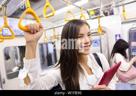 La metropolitana di " commuters " donna giapponese sul trasporto pubblico in Tokyo, Giappone. Tourist utilizzando Giappone della città capitale sistema di metropolitana a commutare. Ritratto di felice asian lady tenendo la maniglia all'interno del carro. Foto Stock