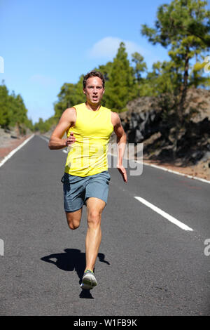 Runner running man in volata per il successo su run. Atleta maschio runner formazione a velocità alta. Muscolare di montare il modello dello sport sprinter esercizio di sprint su strada forestale. Corpo pieno lunghezza del modello caucasico. Foto Stock