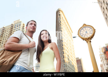 Turismo a NYC - i turisti in visita a New York City in piedi di fronte a Flatiron Building. Coppia giovane di turisti in New York City guardando il famoso punto di riferimento degli edifici durante l'estate. Foto Stock