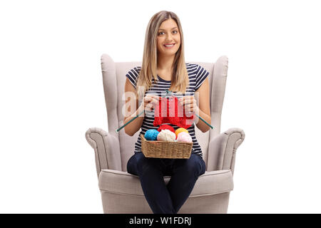 Giovane donna bionda in una poltrona di maglieria e guardando la telecamera isolata su sfondo bianco Foto Stock