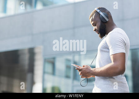 Concentrate l'uomo africano scegliendo melodia al cellulare Foto Stock