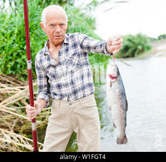 Coppia pescatore con canna da pesca in mano tirando il pesce catturato dal fiume Foto Stock