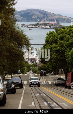 Tipica strada ripida di San Francisco con l'isola di Alcatraz Prision nella baia sul retro, California, Stati Uniti Foto Stock