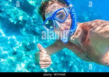 Lo snorkeling subacquea uomo dando pollice in alto segnale di ok che indossa lo snorkel e maschera avendo divertimento sulla spiaggia vacanze estive vacanze godendo di attività ricreative per il tempo libero a nuotare in mare. Foto Stock