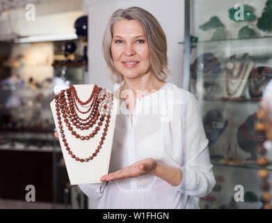 La donna offre di acquistare alla moda di pietra dorata collana in negozio di Gioielleria Foto Stock