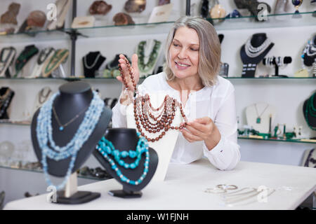 La donna offre di acquistare alla moda di pietra dorata collana in negozio di Gioielleria Foto Stock