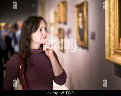 Ritratto di giovane sorridente ragazza attentamente guardando i dipinti in art museum Foto Stock