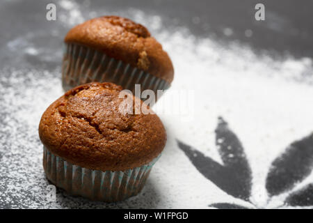 Muffin con la cannabis sul tavolo, uno sfondo scuro. Farina spruzzata sulla superficie, vista dall'alto Foto Stock