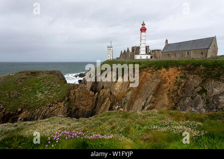 Il Lighthouse e abbey salire al di sopra del mare e coste rocciose a Pointe Saint-Mathieu in Bretagna, Francia Foto Stock
