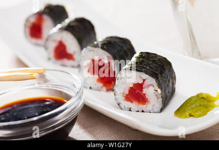 Tonno fresco maki sushi servita su piastra bianca con wasabi e salsa di soia Foto Stock