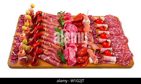 Lo spagnolo gustoso pasto affettamento salsicce fuet, prosciutto, salame, il chorizo con pomodorini e olive alla scrivania in legno, vicino. Isolato su bianco backgroun Foto Stock