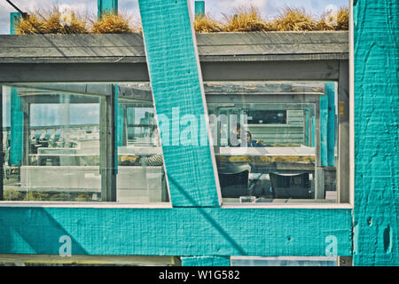 Incorniciato beach hut concentrandosi su due persone accoglienti nell'angolo Foto Stock