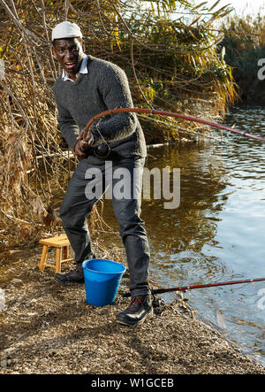 Emotional ritratto di uomo africano tirando con asta di pescare sul fiume Foto Stock