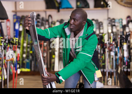 Giovane americano africano in cerca di una nuova attrezzatura da sci in una attrezzatura di sci shop Foto Stock