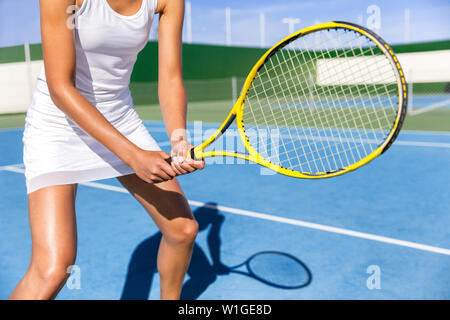 Sezione mediana del giocatore di tennis donna pronto a giocare il gioco su Blu hard court outdoor in posizione azienda racket indossando abito bianco mantello. Atleta femminile ragazza sportiva per sport estivi corso di attività. Foto Stock