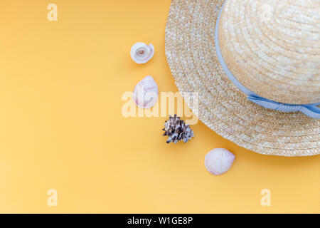 Estate cappello di paglia spiaggia con conchiglie su sfondo giallo.Estate accessori.appartamento spiaggia laici accessori. Concetto per orari estivi e viaggi.una donna Foto Stock