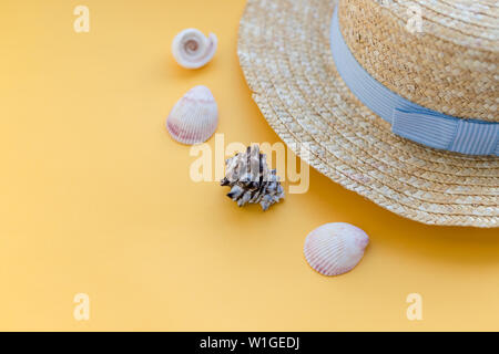 Estate cappello di paglia spiaggia con conchiglie su sfondo giallo.Estate accessori.appartamento spiaggia laici accessori. Concetto per orari estivi e viaggi.una donna Foto Stock