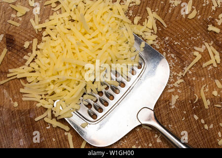 Metallo Grattuggia formaggio e formaggio sul tagliere di legno, Foto Stock