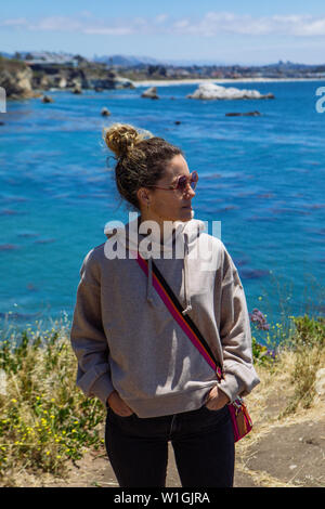 Donna di mezza età che indossa una felpa con cappuccio sportiva con sfumature che si affaccia su un lato con sfondo di Pismo Beach, San Luis Obispo, California, USA Foto Stock