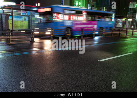 Seoul, Corea del Sud - 30.10.18: il bus passa attraverso la strada notte. il blu autobus arriva alla fermata. illuminazione notturna su asfalto bagnato Foto Stock