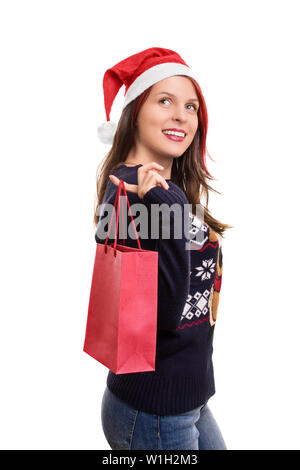 Vacanze, shopping e presenta. Giovane e bella ragazza in abbigliamento invernale, indossando Santa's hat, tenendo in mano un sacchetto della spesa, isolato su sfondo bianco. Foto Stock