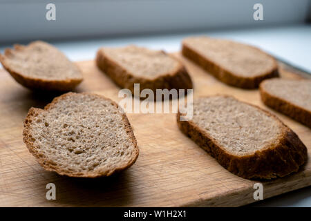 Sei belle fette di pezzi di pane su una tavola di legno su uno sfondo bianco. il malto di pane Foto Stock