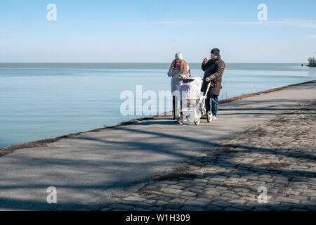 Taganrog, Russia - 05.03.19: il marito e la moglie a piedi con il passeggino lungo il terrapieno. giovane famiglia felice di camminare sul mare. Foto Stock