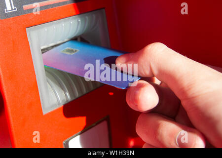 La mano di un uomo con una carta di credito, utilizzando un bancomat. Foto Stock