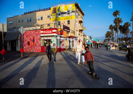 La gente camminare e skater in Venice Beach Boardwalk al tramonto, Los Angeles, California, Stati Uniti d'America Foto Stock