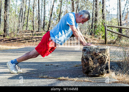 Senior Uomo con sportswear facendo pushups su un allenamento all'aperto Foto Stock