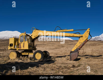 Un vecchio giallo digger era parcheggiata nel mezzo di un prato in Islanda Foto Stock