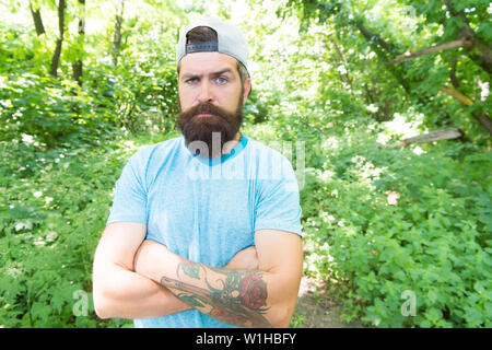 Maschio brutale piacere. Viaggio estivo. Grave barbuto uomo maturo in ambiente naturale. Barbuto ragazzo nella foresta del parco. Barbuto macho. Hipster con barba lunga faccia emotivo da vicino la natura dello sfondo. Foto Stock