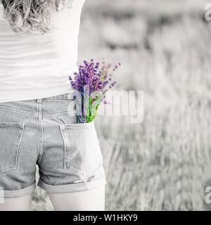 Bouquet di porpora viola Lavanda fiori nella tasca dei jeans. Foto in bianco e nero, luminoso bouquet. Spazio di copia Foto Stock