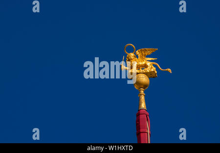 San Marco leone alato golden statuetta brandendo una spada contro il cielo blu, un simbolo della Vecchia Repubblica di Venezia in guerra (con copia spazio) Foto Stock