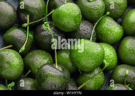 Close-up di un sacco di ciliegie mature, colore insolito calce. bellissimo colore verde brillante background. Foto Stock