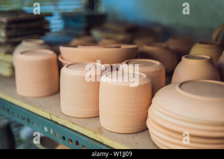 Tazze sui ripiani nel laboratorio di ceramica Foto Stock